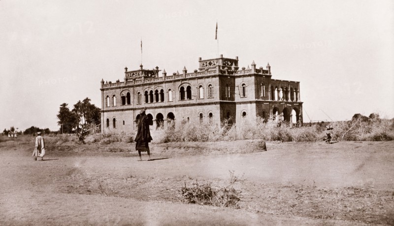 Government House at Wad Madani. View of Government House at Wad Madani, a large, two-storey building with rounded arch windows, pinnicles along its parapet, and two square towers. Wad Madani, Sudan, circa 1910. Wad Madani, Al Jazirah, Sudan, Eastern Africa, Africa.