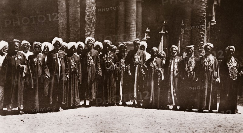 Sheikhs of the Red Sea State, Sudan. A number of Sudanese Sheikhs line up for a group portrait outside a brick building, dressed in matching robes and turbans. Red Sea State, Sudan, circa 1910., Red Sea, Sudan, Eastern Africa, Africa.