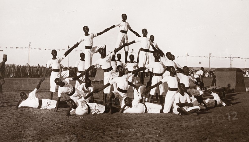 Sudanese military cadets. A group of young Sudanese army cadets, dressed in white uniforms, form a human pyramid during an outdoor display at a military school. Khartoum, Sudan, circa 1910. Khartoum, Khartoum, Sudan, Eastern Africa, Africa.