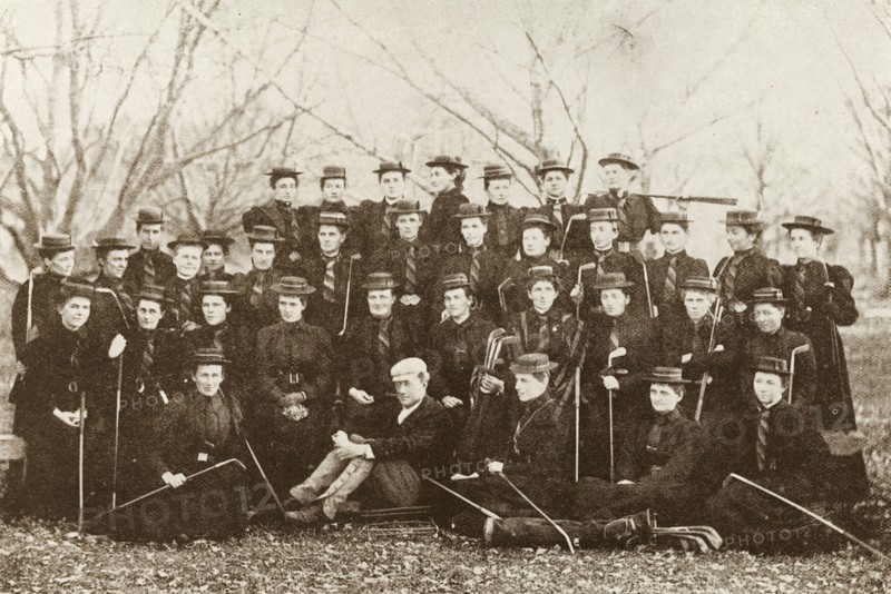 New Zealand ladies' golf teams. A photograph printed in 'The Sketch' newspaper features women from the Christchurch and Dunedin ladies' golf teams, posing for a group portrait with their golf clubs. The women wear a uniform of dark dresses, striped ties and boater hats. Probably Christchurch, New Zealand, 1895. Christchurch, Canterbury, New Zealand, New Zealand, Oceania.