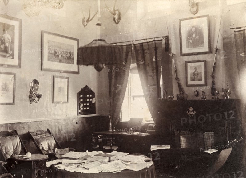 Ante room in a British Army mess building. Interior shot of an ante room in a British Army mess building, used by off-duty soldiers as a place to relax and socialise. Framed pictures and mounted antelope skulls adorn the walls, whilst padded chairs surround a table sprawling with papers. Chaman, Baluchistan, India (Balochistan, Pakistan), 1905. Chaman, Balochistan, Pakistan, Southern Asia, Asia.
