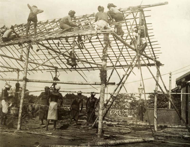 Building a spectator stand for the royal visit. A team of Ceylonian men construct the frame of a spectator stand in preparation for a visit from the Duke and Duchess of Cornwall and York (later King George V and Queen Mary). The royal couple stopped in Ceylon (Sri Lanka) on their way to open the first Commonwealth Parliament of Australia in Melbourne. Colombo, Ceylon (Sri Lanka), 1901. Colombo, West (Sri Lanka), Sri Lanka, Southern Asia, Asia.