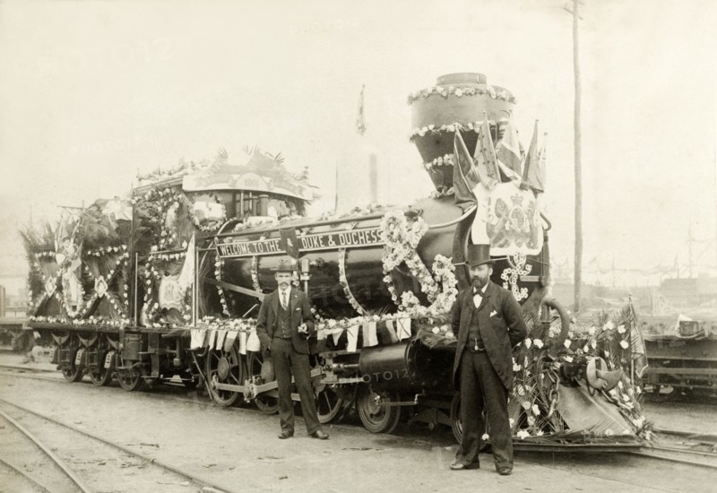 Royal train at Perth. Two men stand beside a locomotive, decorated with flowers and bunting for the arrival of the Duke and Duchess of Cornwall and York (later King George V and Queen Mary) from Albany. Perth, Australia, July 1901. Perth, West Australia, Australia, Australia, Oceania.