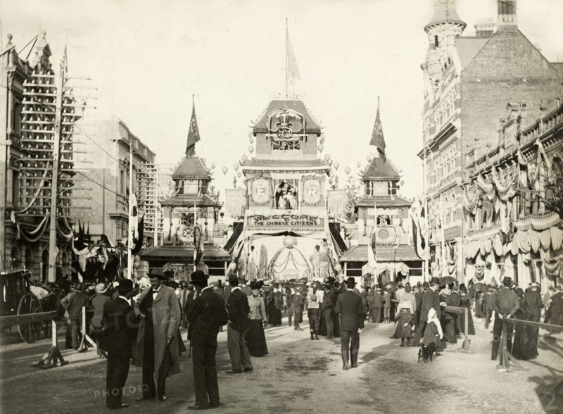 Awaiting the royal welcome procession, Perth. Crowds mill about on the street in front of a decorative arch in Perth's China Town district, as they await a welcome procession for the Duke and Duchess of Cornwall and York (later King George V and Queen Mary). Perth, Australia, July 1901. Perth, West Australia, Australia, Australia, Oceania.