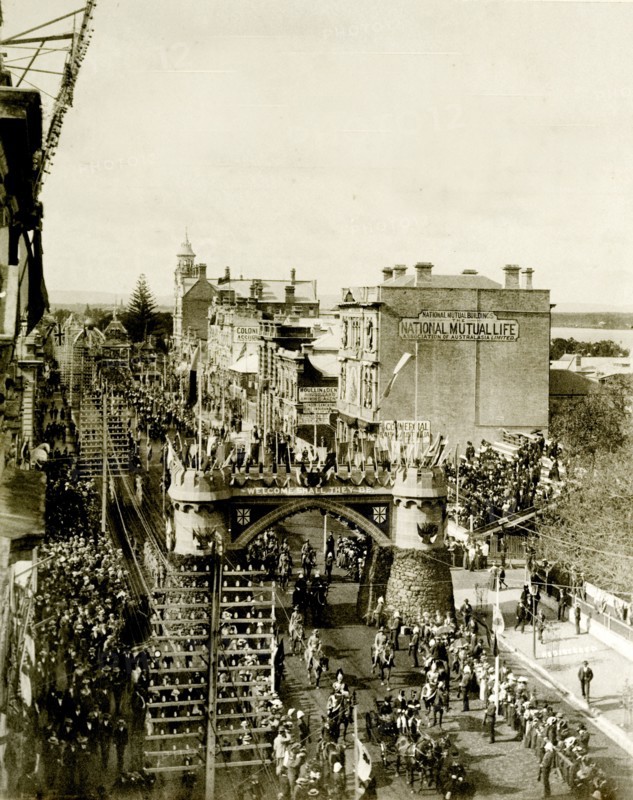 Royal procession beneath the Coach Arch. A procession for the Duke and Duchess of Cornwall and York (later King George V and Queen Mary) passes beneath the Coach Arch at St. George's Terrace. Crowds flank the streets as the parade passes. Perth, Australia, July 1901. Perth, West Australia, Australia, Australia, Oceania.