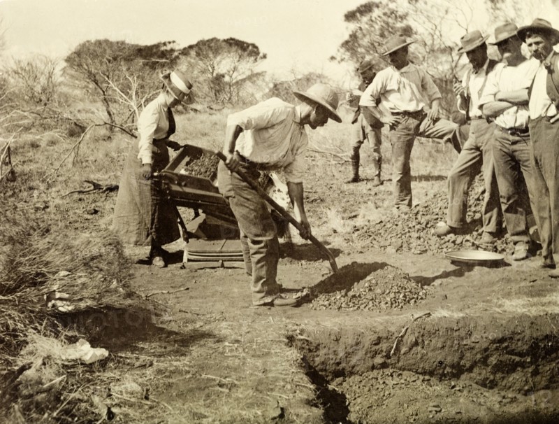 The Lawleys at Laverton gold fields. Sir Arthur Lawley, Governor of Western Australia, shovels earth onto a gold shaker operated by his wife, Lady Annie Lawley, whilst a team of miners look on. The machine was designed to sift through dirt and gravel, carrying the heavier gold to the bottom. Laverton, Australia, circa 1901. Laverton, West Australia, Australia, Australia, Oceania.