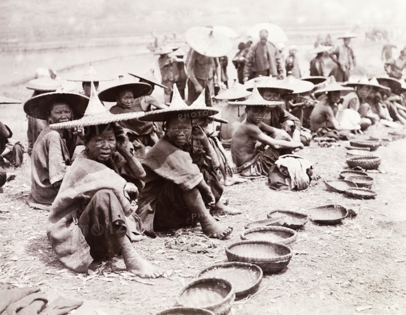 Mendicants beg by the roadside, China. A number of mendicants, some of whom are suffering from leprosy, beg at the roadside with their woven bowls. Both men and women wear wide-brimmed conical hats. Shikuan, Yunnan Province, China, circa 1905. Shikuan, Yunnan, China, People's Republic of, Eastern Asia, Asia.