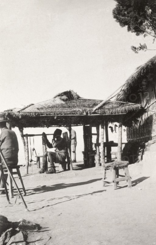 On watch at 'Pagoda Hill'. A Burmese man dressed in military uniform and a fez hat sits on a stool beneath a thatched canopy, peering through a long telescope. An original caption gives the location as 'Pagoda Hill', possibly a reference to the Kakku Pagodas located near Taunggyi. Taunggyi, Burma (Myanmar), December 1928. Taunggyi, Shan, Burma (Myanmar), South East Asia, Asia.