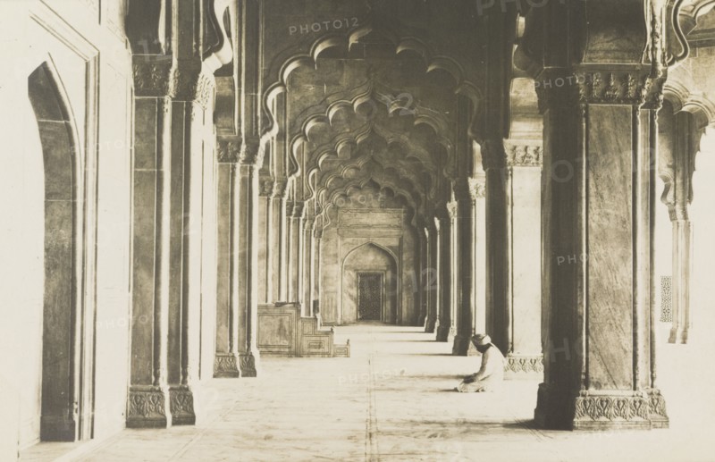Contemplation at the Moti Masjid, Agra. View of a colonnaded aisle inside the Moti Masjid (Pearl Mosque) at Agra Fort. A man wearing a turban sits cross-legged on the floor beneath the lobed arches, his head bent in contemplation. Agra, United Provinces (Uttar Pradesh), India, circa 1922. Agra, Uttar Pradesh, India, Southern Asia, Asia.