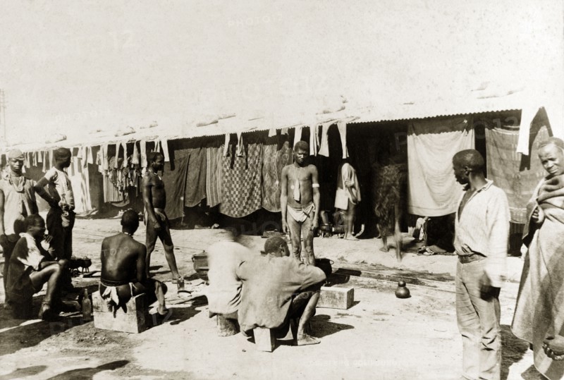 Off-duty diamond mine workers. African workers from the De Beers diamond mine rest outside their living quarters at the Kimberley compound. Kimberley, South Africa, circa 1896. Kimberley, North Cape, South Africa, Southern Africa, Africa.