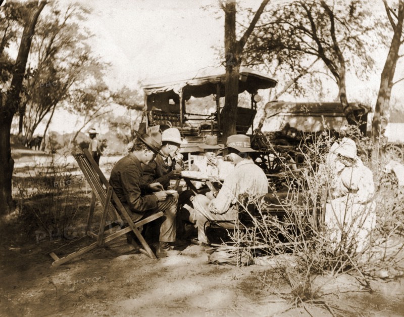 Captain Lawley stops for lunch. Captain Arthur Lawley (1860-1932) (front right) takes lunch with fellow European travellers during an overland journey from South Africa to Rhodesia. Accompanied by Earl Grey (1851-1917), he was travelling with relief forces and supplies to Bulawayo, which had been besieged during the Matabele rebellion. Probably Bechuanaland (Botswana), circa March 1896. Botswana, Southern Africa, Africa.