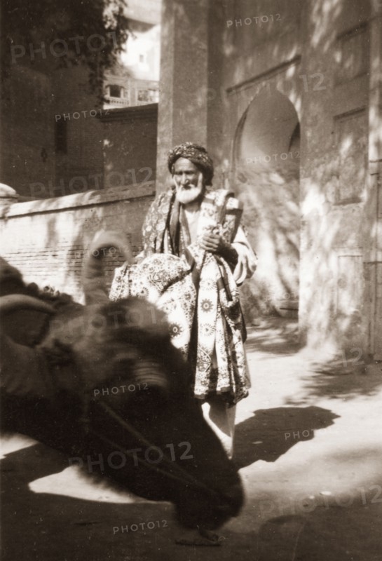 An Indian rug vendor. An elderly street trader touts a variety of patterned rugs as he wanders around the city streets looking for custom. North West Frontier Province, India (Pakistan), circa 1927., North West Frontier Province, Pakistan, Southern Asia, Asia.