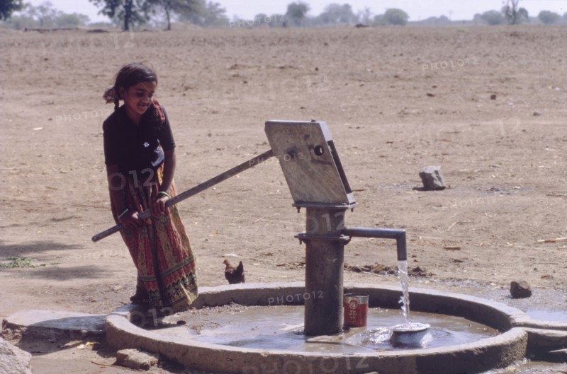 Raising water from a borewell. A young girl operates a hand pump to raise water from a borewell. Andhra Pradesh, India, circa 1985., Andhra Pradesh, India, Southern Asia, Asia.