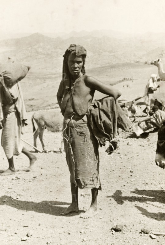 Portrait of an Eritrean woman. Portrait of a middle-aged Eritrean woman at an outdoor camel market. Naked from the waist up, she stands barefoot with her hands on her hips, an empty sack slung over one arm. Eritrea, 1943. Eritrea, Eastern Africa, Africa.