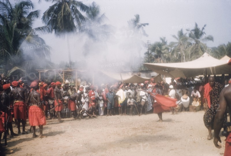Asafo company firing guns. Members of Asafo Number Two Company swing flags and fire guns at a ceremony in Lowtown. Saltpond, Ghana, April 1960. Saltpond, West (Ghana), Ghana, Western Africa, Africa.