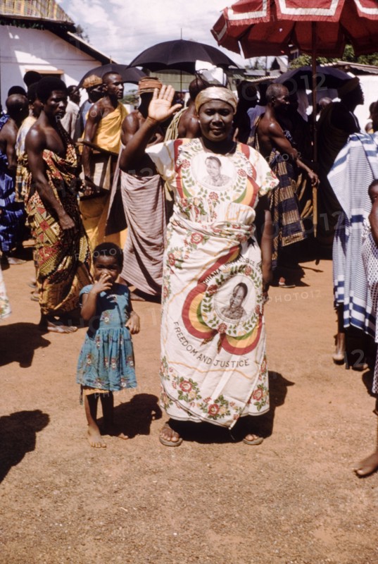 Independence cloth. A smiling woman wears a wrap-around cloth printed with the image of the Ghanaian politican Kwama Nkrumah (1909-1972), during celebrations to mark Ghana becoming a Republic under the Nkrumah's presidency. Saltpond, Ghana, circa 1960. Ghana, Western Africa, Africa.