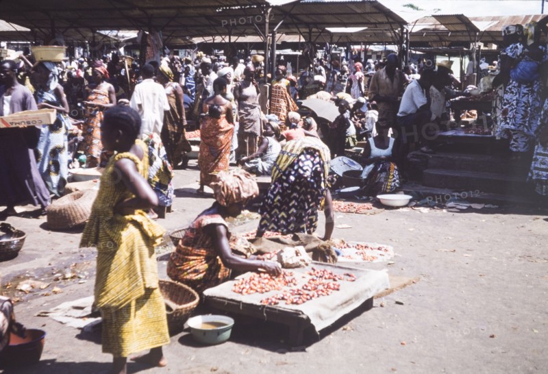 Kola nut stall at Abidjan market. Women arrange a display of kola nuts at a bustling market in Abidjan. Abidjan, Cote d'Ivoire, circa 1960. Abidjan, Lagunes, Cote d'Ivoire, Western Africa, Africa.