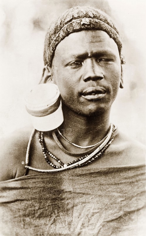 Portrait of a Maasai man. Head and shoulders portrait of a Maasai man, wearing traditional jewellery including a large ear ornament. British East Africa (Kenya), circa 1912. Kenya, Eastern Africa, Africa.