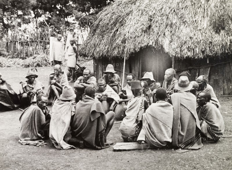A meeting of Kikuyu elders. A group of Kikuyu men gather in a circle to drink beer from a hollow bullock's horn, a privilege granted only to tribal elders. Nyeri, Kenya, 1936. Nyeri, Central (Kenya), Kenya, Eastern Africa, Africa.