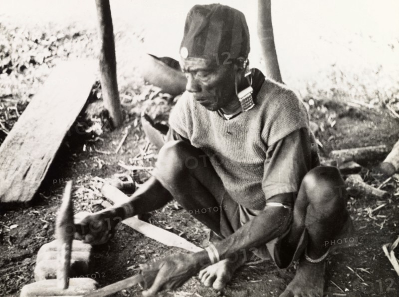 A Kikuyu metalsmith. A Kikuyu metalsmith hammers a knife blade into shape using an anvil in his workshop. Nyeri, Kenya, 1936. Nyeri, Central (Kenya), Kenya, Eastern Africa, Africa.