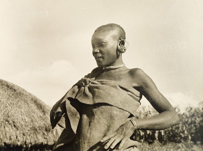 A married Kikuyu woman. Portrait of a married Kikuyu woman, dressed in a wrap-around cloth tied at the shoulder with jewellery including hooped earrings, a beaded necklace and a bracelet. Nyeri, Kenya, 1936. Nyeri, Central (Kenya), Kenya, Eastern Africa, Africa.