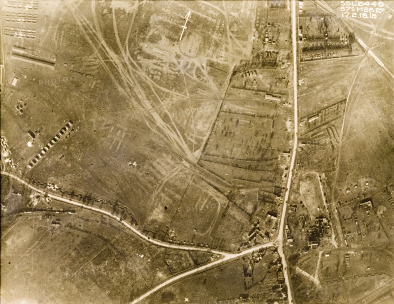 Aerial view of a camoflauge depot. One of a series of British aerial reconnaissance photographs recording the positions of trenches on the Western Front during the First World War. Square-toothed trenches surround a bomb-damaged village. An original caption indicates the position of a camouflage depot and train in the bottom left hand corner. Nord-Pas de Calais or Picardie, France, 17 February 1918., Nord-Pas de Calais, France, Western Europe, Europe .