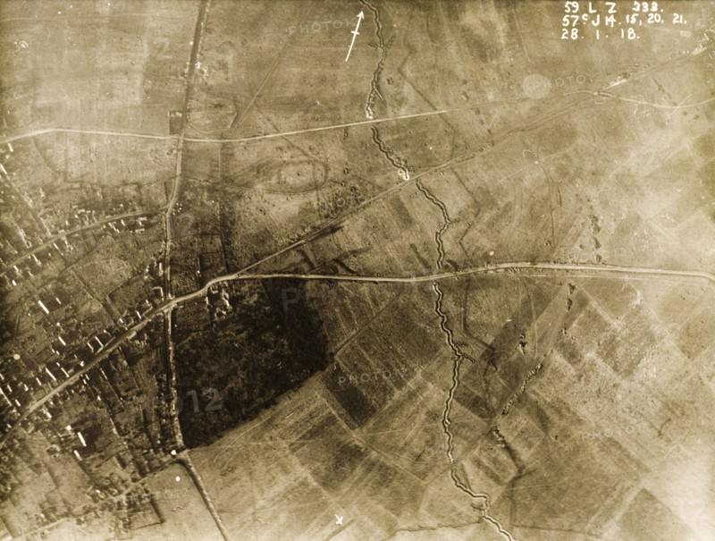 Ruined village behind a British defence trench. One of a series of British aerial reconnaissance photographs recording the positions of trenches on the Western Front during the First World War. A bomb-damaged village lies behind a British defence trench, which zig-zags its way across the fields protected by a line of barbed wire. An original caption identifies the positions of a number of field guns, stationed beside the roads leading into the village. Nord-Pas de Calais or Picardie, France, 28 January 1918. France, Western Europe, Europe .