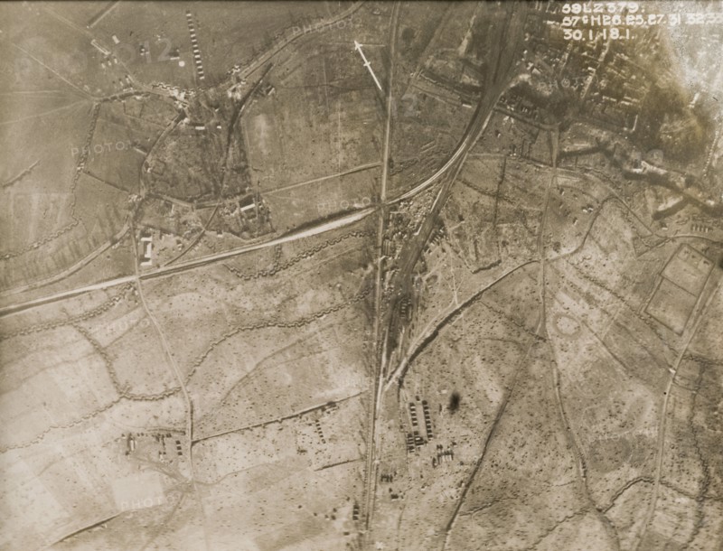 A military camp at a bomb-damaged village. One of a series of British aerial reconnaissance photographs recording the positions of trenches on the Western Front during the First World War. Sqaure-toothed trenches encircle a military camp, probably British, on the outskirts of a bomb-damaged village. The surrounding fields are peppered with shell blasts after suffering a continuous barrage of artillery fire. Nord-Pas de Calais or Picardie, France, 30 January 1918., Nord-Pas de Calais, France, Western Europe, Europe .