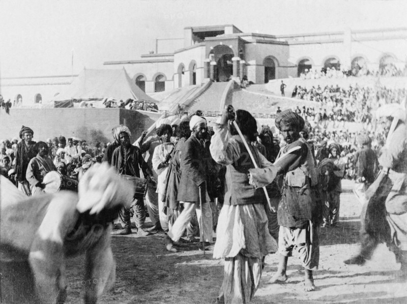 A display of swordsmanship. Musicians play as two swordsmen spar at an outdoor event. Sukkur, Sind, India (Sindh, Pakistan), circa 1908. Sukkur, Sindh, Pakistan, Southern Asia, Asia.