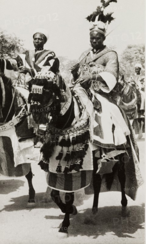 Nigerian chief riding a caparisoned horse. A Nigerian chief wearing an elaborate feathered headdress rides a caparisoned horse during celebrations for Sallah, an Islamic event held to mark the end of Ramadan. Nigeria, circa 1948. Nigeria, Western Africa, Africa.