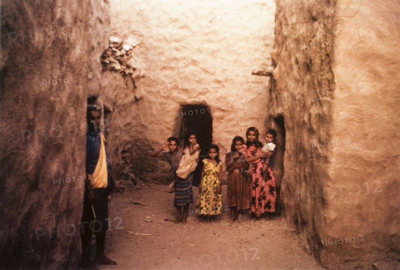 A group of children in Yemen. A group of children pose for the camera in an alcove formed by mud-walled buildings. Lodar, Yemen, circa 1963., Abyan, Yemen, Middle East, Asia.
