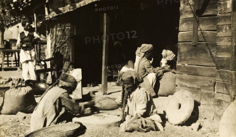 Indian millers at work. A group of men sit outdoors as they grind grain by hand using millstones. India, circa 1915., India, Southern Asia, Asia.