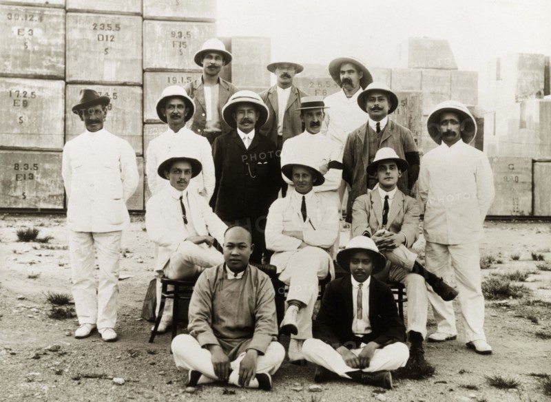 Civil engineers at the Hong Kong docks. A team of British and Chinese civil engineers pose for a group portrait. They were completing construction work at the Hong Kong docks under the supervision of Major Paul Dashwood (seated, centre). Hong Kong, China, 1919. Hong Kong, Hong Kong, China, People's Republic of, Eastern Asia, Asia.
