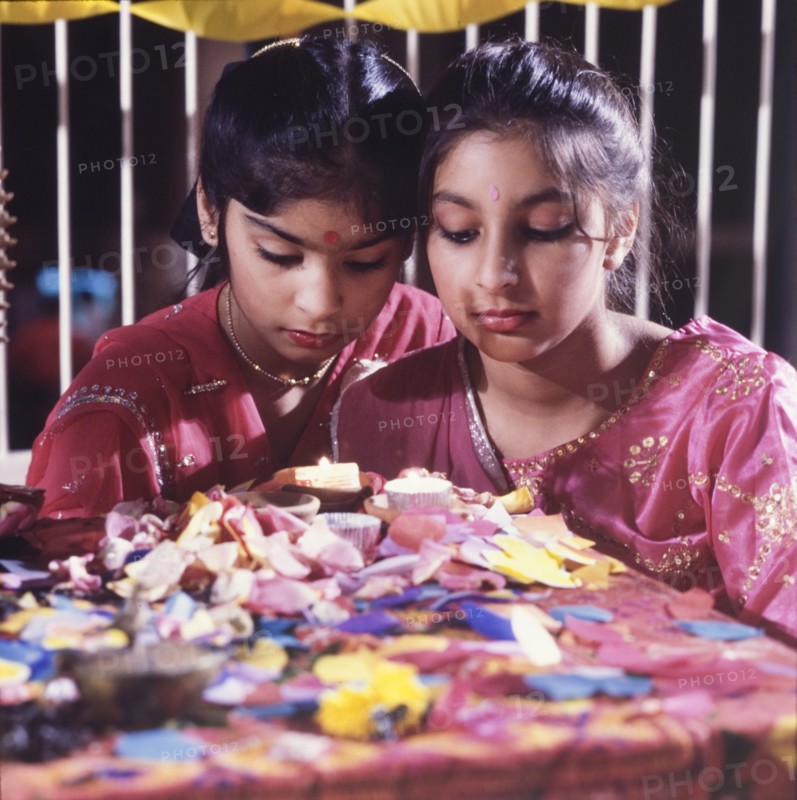 Candles for Diwali. Two girls in traditional Indian dress light candles for Diwali, the Hindu festival of light, during a mela (fair) at the Commonwealth Institute. London, England, circa 1985. London, London, City of, England (United Kingdom), Western Europe, Europe .