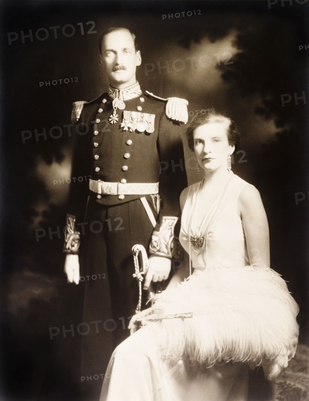 Sir Bede and Lady Clifford. Studio portrait of Sir Bede Edmund Hugh Clifford, Governor of the Bahamas, and his wife, Lady Clifford. The couple are dressed in formal attire: Sir Bede in full military regalia, his wife in a white evening gown with an ostrich feather fan. Bahamas, circa 1932. Bahamas, Atlantic Ocean, Africa.