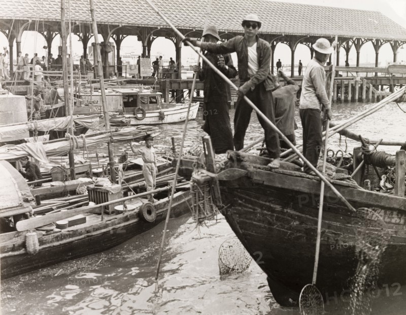 Fishing in a Hong Kong harbour. Fishermen stand at the bow of their sampan, dipping long-handled fishing nets into the waters of a Hong Kong harbour. Hong Kong, China, 1963., Hong Kong, China, People's Republic of, Eastern Asia, Asia.