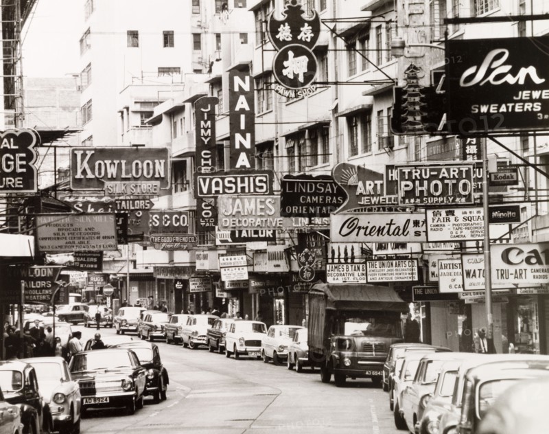 Cameron Road, Kowloon. English shop signs and advertisements vie for attention on Cameron Road in the heart of the tourist shopping district. Kowloon, Hong Kong, China, 1963. Kowloon, Hong Kong, China, People's Republic of, Eastern Asia, Asia.