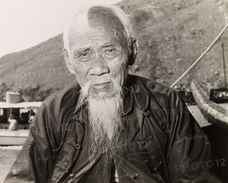 An elderly Chinese fisherman. Portrait of an elderly fisherman sitting on a boat in a Hong Kong harbour. Hong Kong, China, 1963. Hong Kong, Hong Kong, China, People's Republic of, Eastern Asia, Asia.