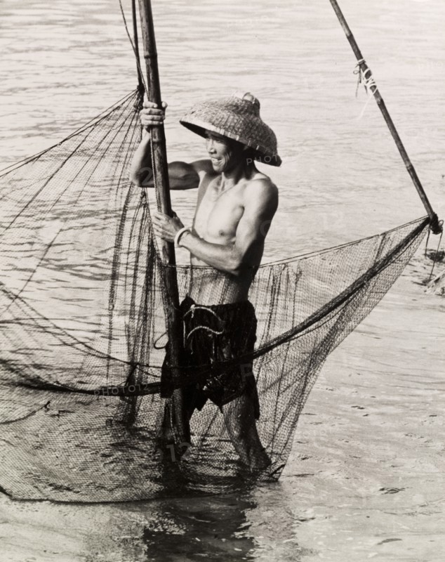 Fishing in shallow waters. A fisherman trawls his net in the shallow waters of a Hong Kong bay. Hong Kong, China, 1963., Hong Kong, China, People's Republic of, Eastern Asia, Asia.