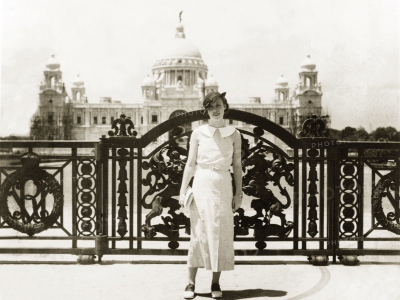 Posing outside Victoria Memorial Hall. A European woman poses in front of the ornate gateway to Victoria Memorial Hall, an imperial building built to commemorate Queen Victoria. Completed in 1921, it was designed by British architect Sir William Emerson in a fusion of European and Mughal architectural style. Calcutta (Kolkata), India, April 1935. Kolkata, West Bengal, India, Southern Asia, Asia.