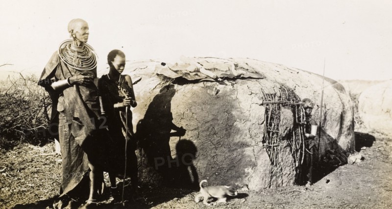 A traditional Maasai hut. A Maasai woman and two children stand beside a traditional Maasai wattle and daub hut in the Sanya Plains. Kilimanjaro, Tanganyika Territory (Tanzania), 21 September 1930., Kilimanjaro, Tanzania, Eastern Africa, Africa.