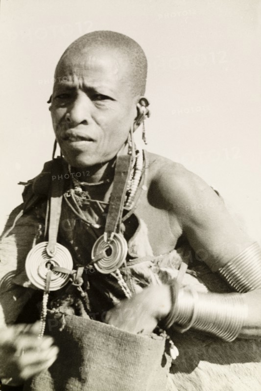 Kikuyu woman wearing traditional jewellery. Portrait of a Kikuyu woman wearing traditional jewellery including copper armbands and elaborate ear decorations. Kenya, circa 1932. Nyeri, Central (Kenya), Kenya, Eastern Africa, Africa.