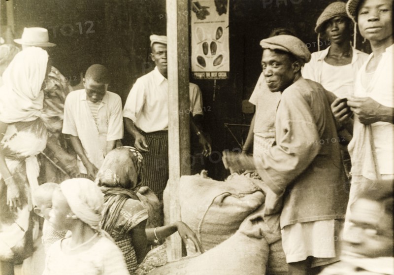 Weighing sacks of cocoa. Sacks of cocoa are weighed at a cooperative warehouse in preparation for exportation. Gold Coast (Ghana), circa 1950. Ghana, Western Africa, Africa.