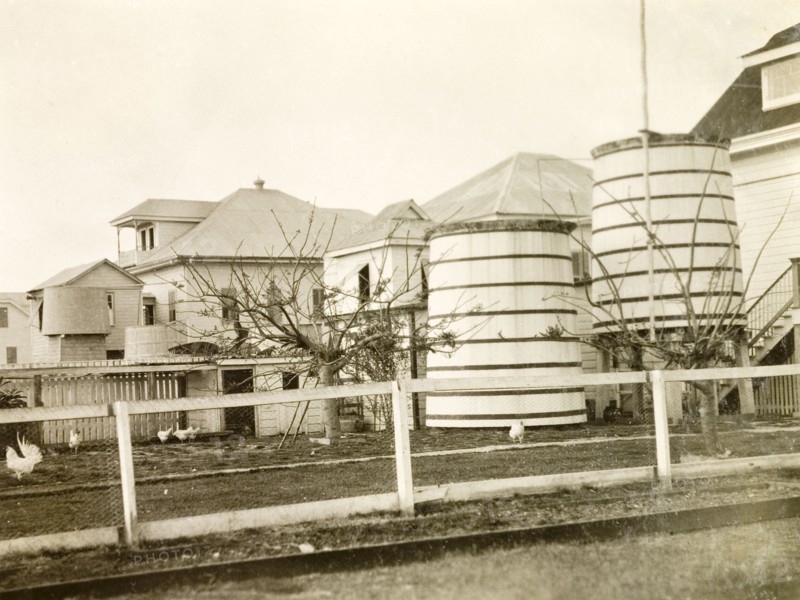 Water butts in a colonial garden, Belize. The rear garden of a colonial house, containing a chicken coup and two large rainwater containers. Belize, 1931. Belize, Central America, North America .