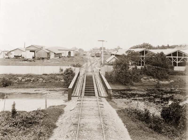 Railway tracks entering Port of Spain. A railway track crosses a river bridge on its approach to the railway terminus at Port of Spain. Port of Spain, Trinidad, circa 1912. Port of Spain, Trinidad and Tobago, Trinidad and Tobago, Caribbean, North America .