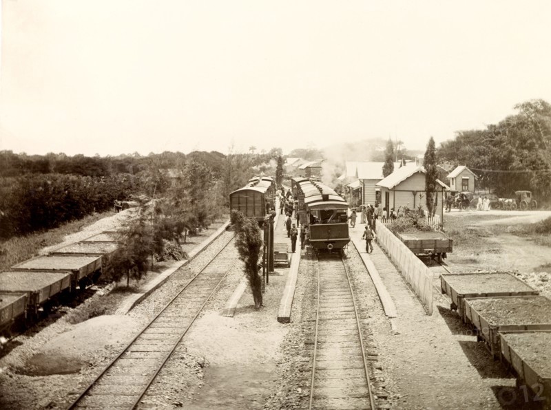 San Joseph railway station, Trinidad. Flatbed freight cars loaded with gravel sit beside passenger carriages at San Joseph railway station. San Joseph, Trinidad, circa 1912., Trinidad and Tobago, Trinidad and Tobago, Caribbean, North America .