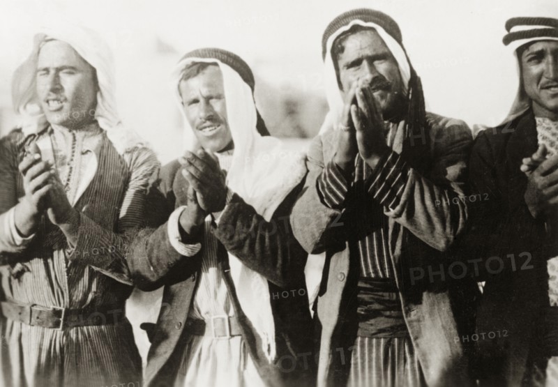 Pilgrims at a Nebi Musa procession. Four Arab men clap their hands together as they take part in a Nebi Musa procession: an annual pilgrimage made by Palestinian Muslims to Nebi Musa near Jericho, the supposed burial place of Moses. Ramallah, British Mandate of Palestine (West Bank, Middle East), circa 1938. Ramallah, West Bank, West Bank (Palestine), Middle East, Asia.