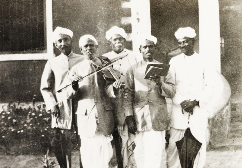 A Methodist evangelist band. Group portrait of a Methodist evangelist band, who sing a song from a hymn book to the accompaniment of a violin. Tumkur, Mysore State (Tumakuru, Karnataka), India, circa 1933., Karnataka, India, Southern Asia, Asia.