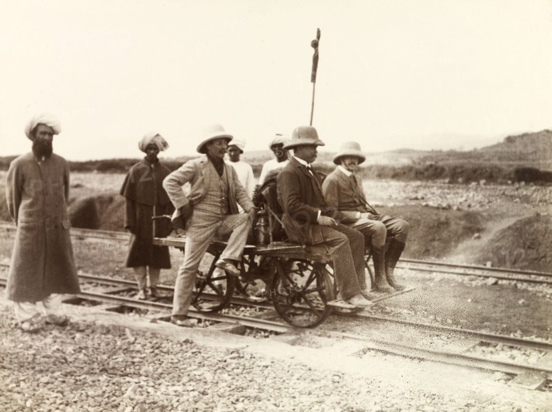 Rail cart on Kohat-Thal railway line. Three European men sit on a hand-operated rail cart on the Kohat-Thal railway line, attended to by four Indian servants and railway workers. North West Frontier Province, India (Pakistan), February 1903., North West Frontier Province, Pakistan, Southern Asia, Asia.