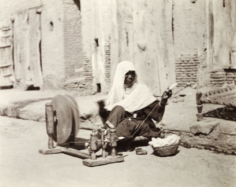 Silk spinner, India. An Indian woman sits by the roadside spinning silk using a 'charkha' or spinning wheel. United Provinces (Uttar Pradesh), India, January 1903., Uttar Pradesh, India, Southern Asia, Asia.